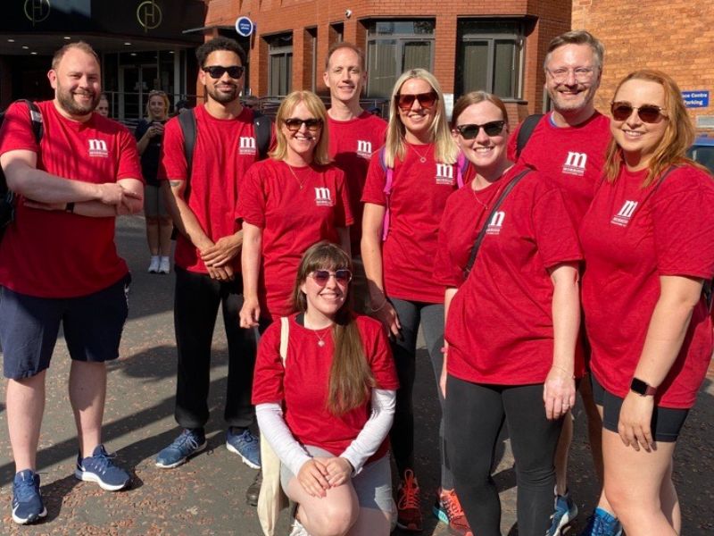 The image shows 9 people in red Morrish tshirts standing outside the Morrish office in Leeds city centre